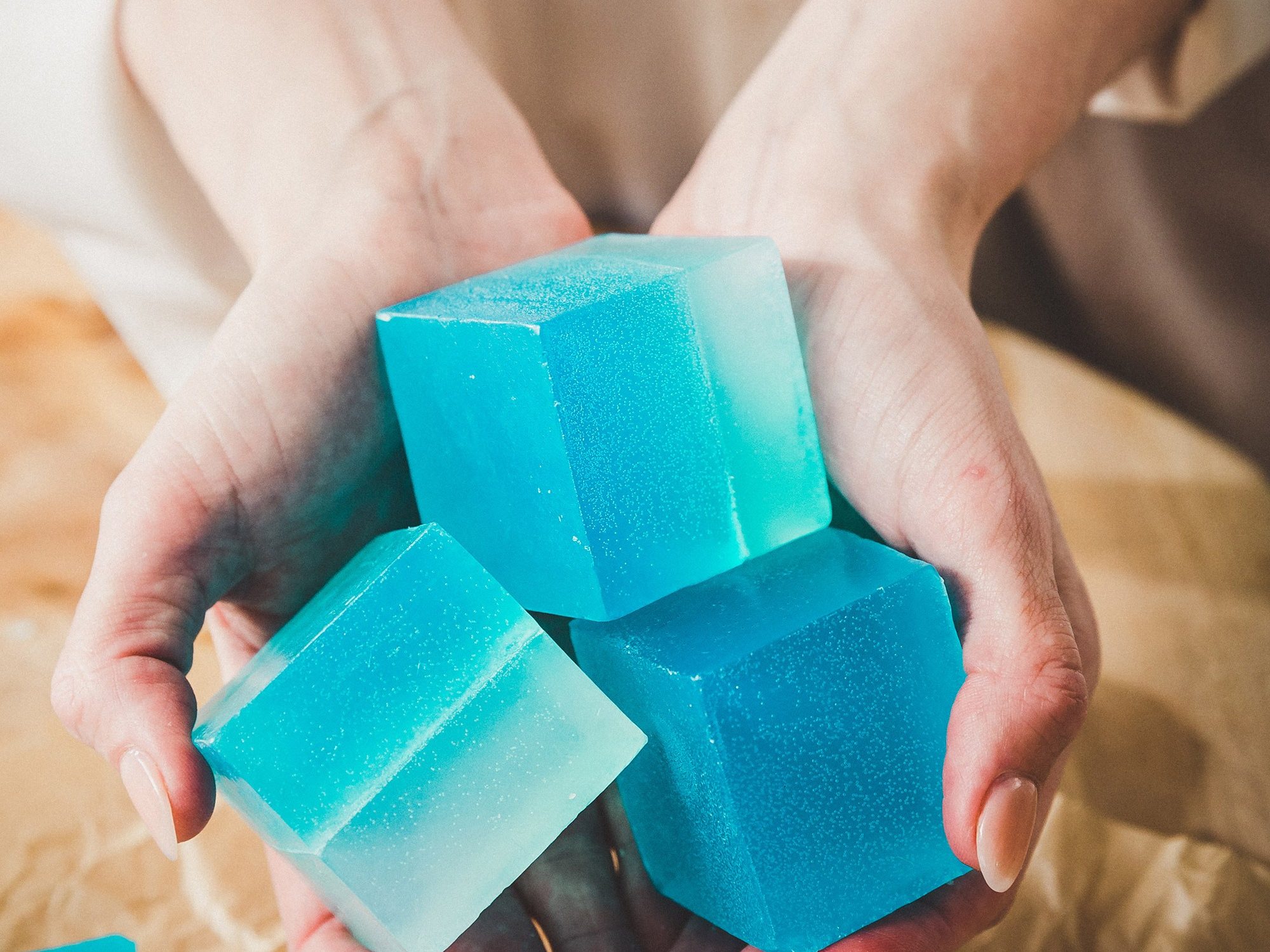 Cubes of bright blue soap being held out in someone's hands.