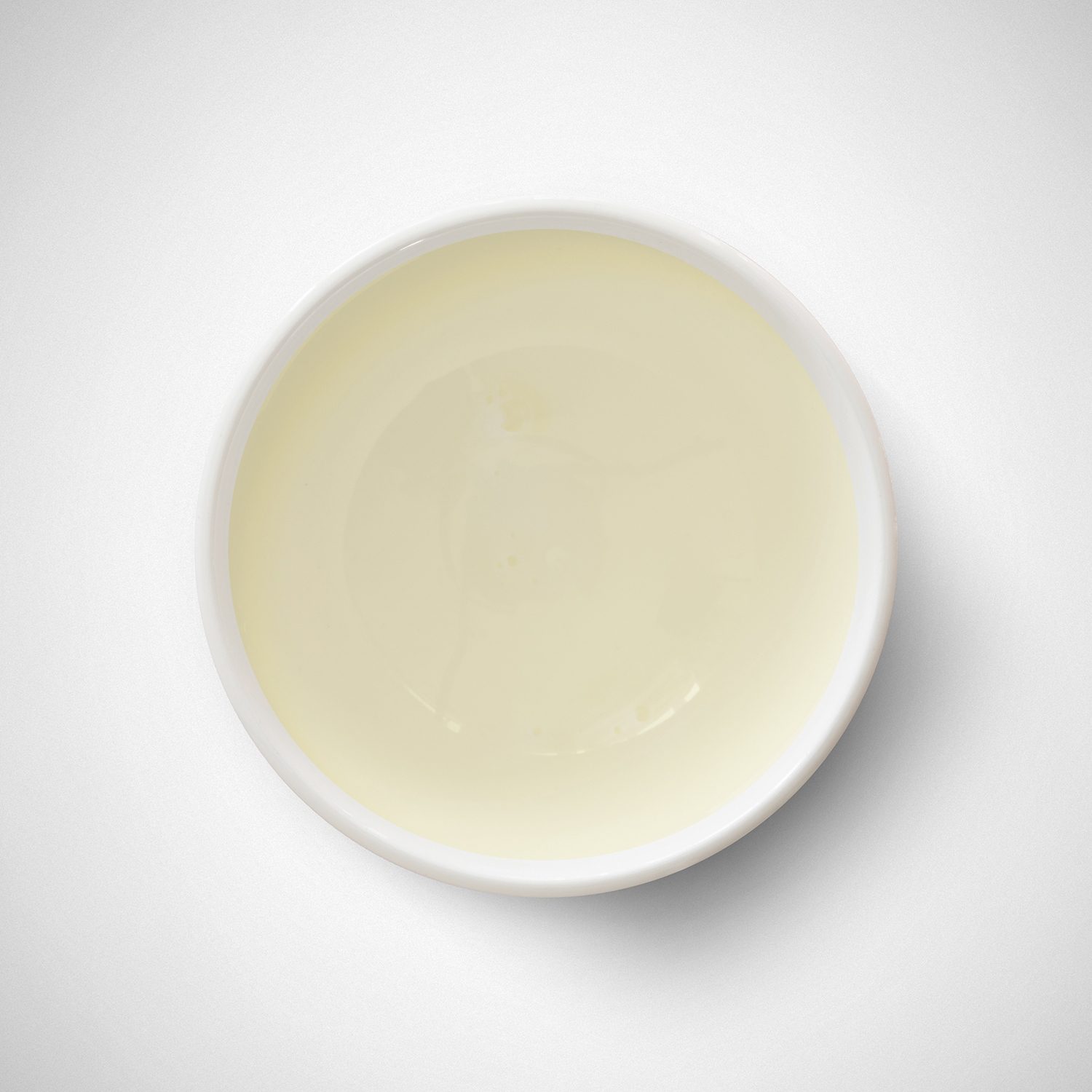 Creamy liquid in a small bowl on a white background.
