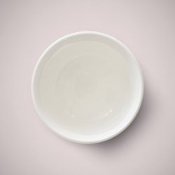 Melt and pour soap in a small bowl on a pale pink surface.