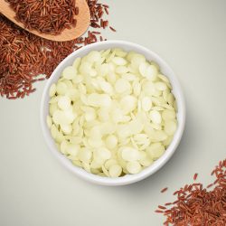 A bowl of rice brand wax beads on a surface surrounded by brown rice – supplied by 1875.